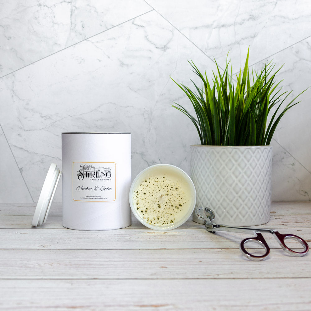 White cylindrical amber and spice candle with speckled wax and silver lid by the stirling candle company