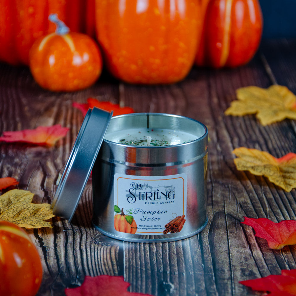 Silver tin pumpkin spice travel candle with cotton wick white wax green speckles and cinnamon stick label by stirling candle company