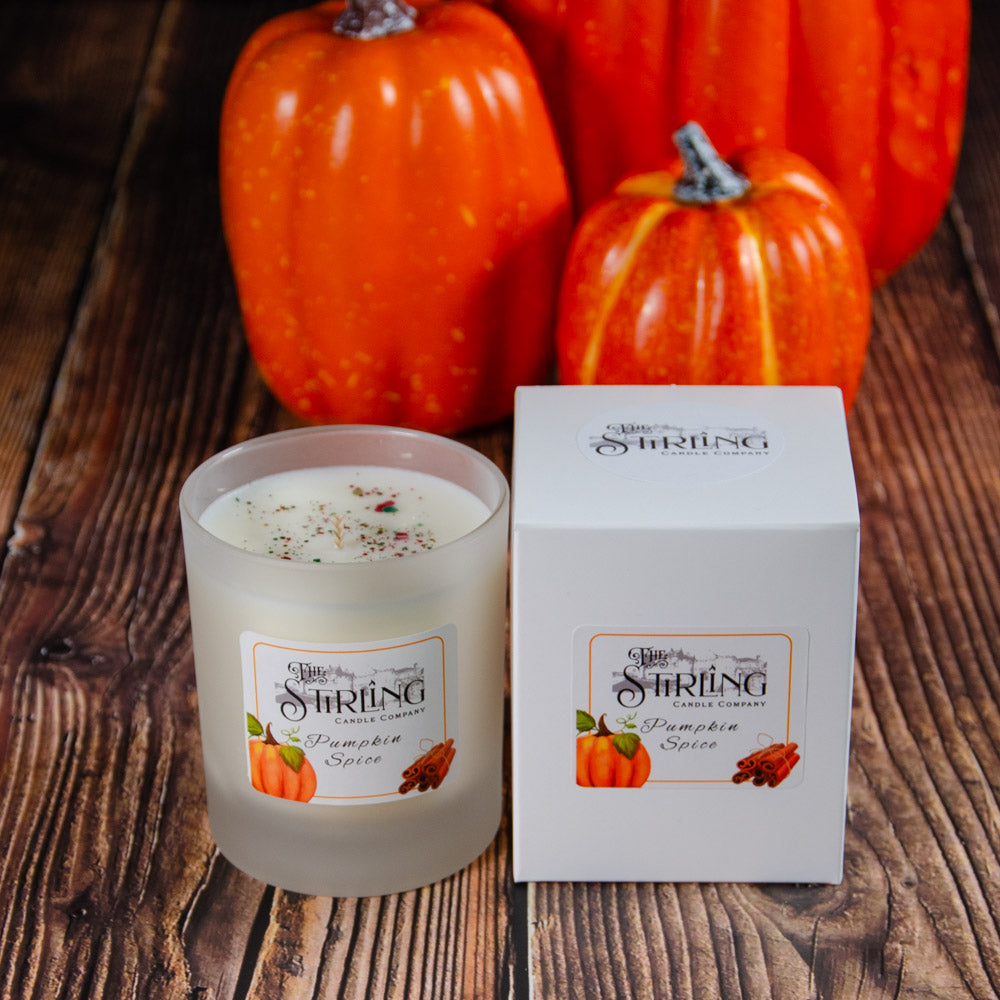 A frosted glass medium candle with speckled wax and cinnamon stick label in pumpkin spice scent by Stirling Candle Company