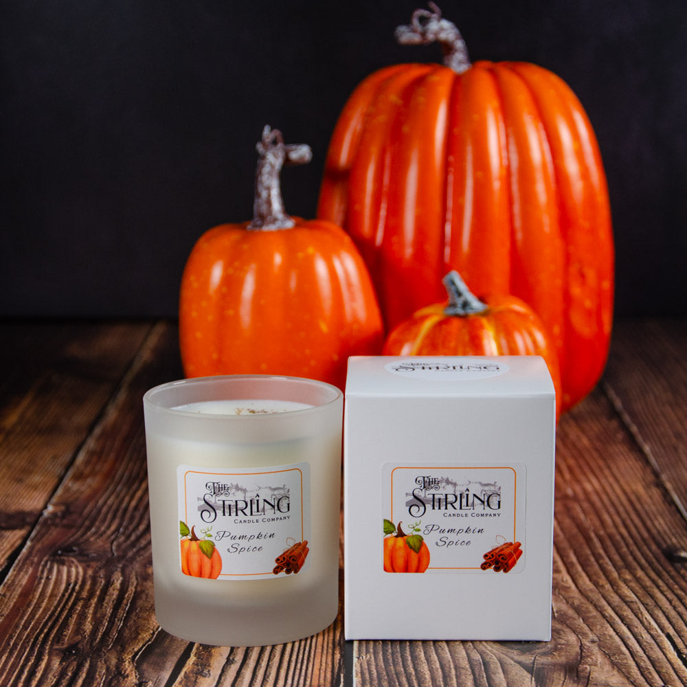 A frosted glass pumpkin spice medium candle from stirling candle company with matching box and orange pumpkins