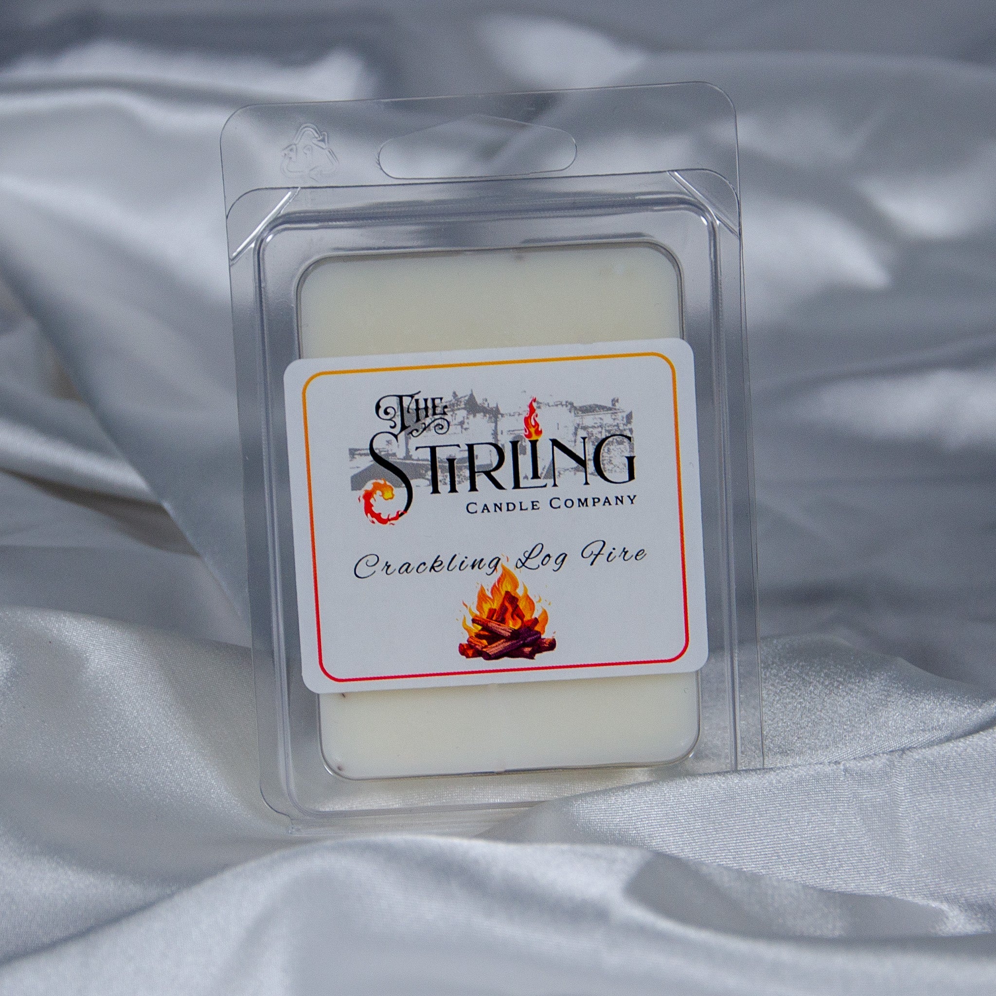 A creamy white crackling log fire wax melt in a clear plastic clamshell by Stirling Candle Company
