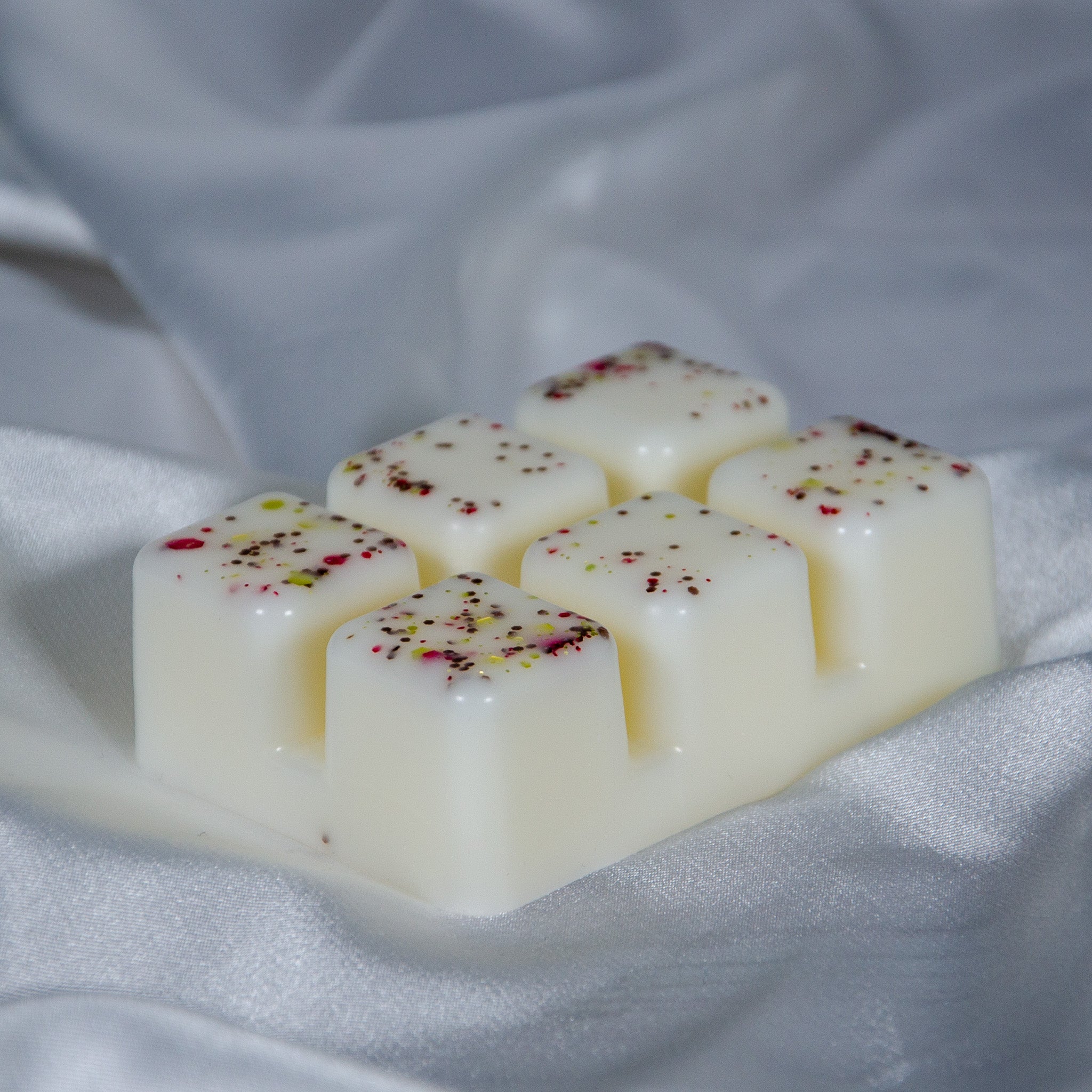 Six cream-colored wax melts with red and green flecks in a crackling log fire wax melt clamshell set