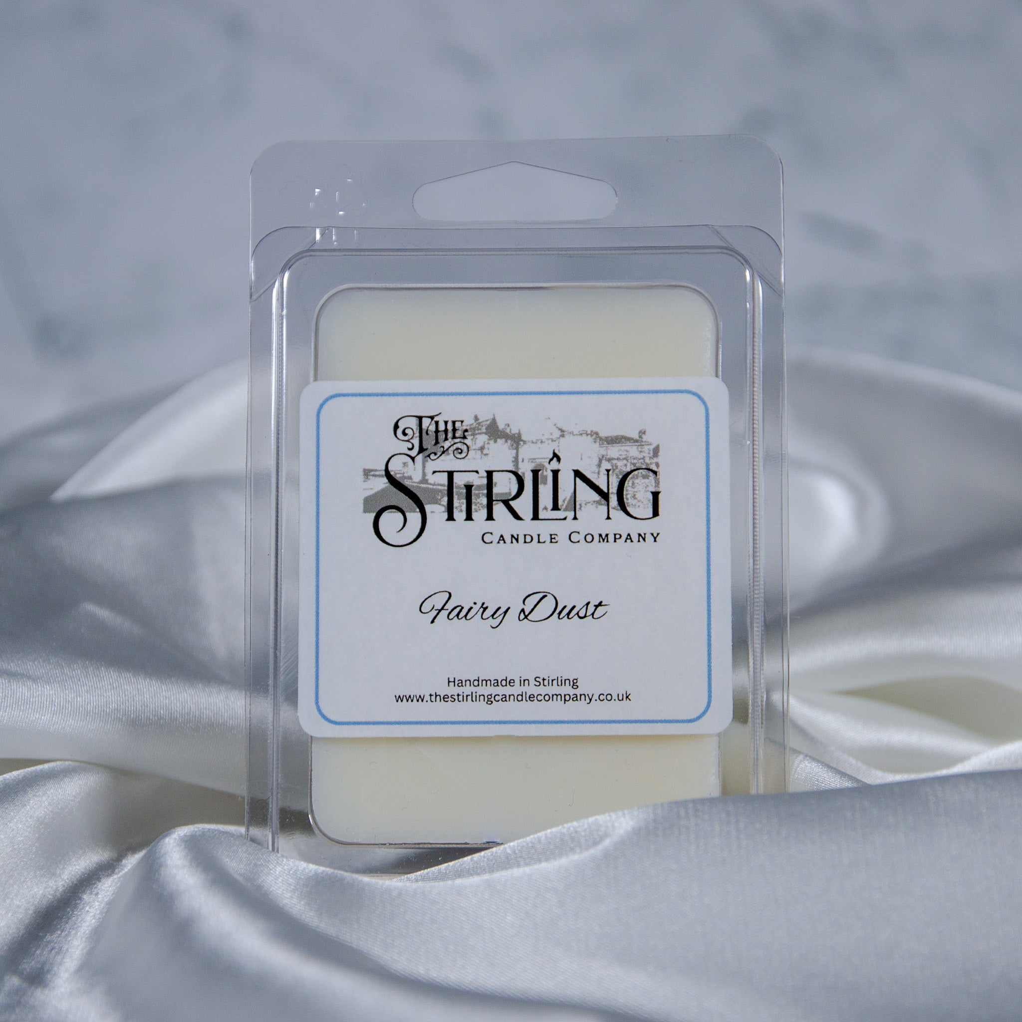 A creamy white fairy dust wax melt clamshell in a clear plastic package with a label from stirling candle company