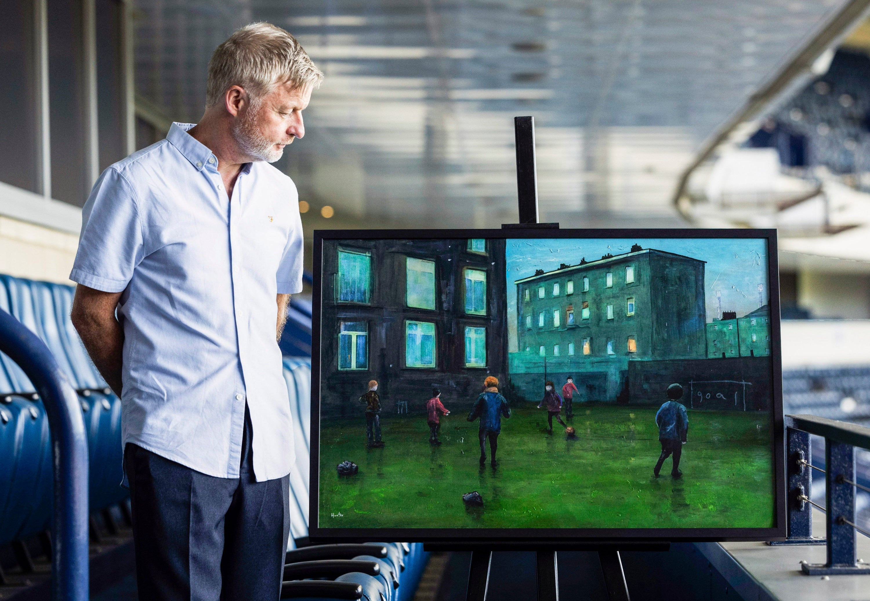 Man observing a painting displayed on an easel for the Time A Painting for SFA Hampden Stadium and Adult Voices