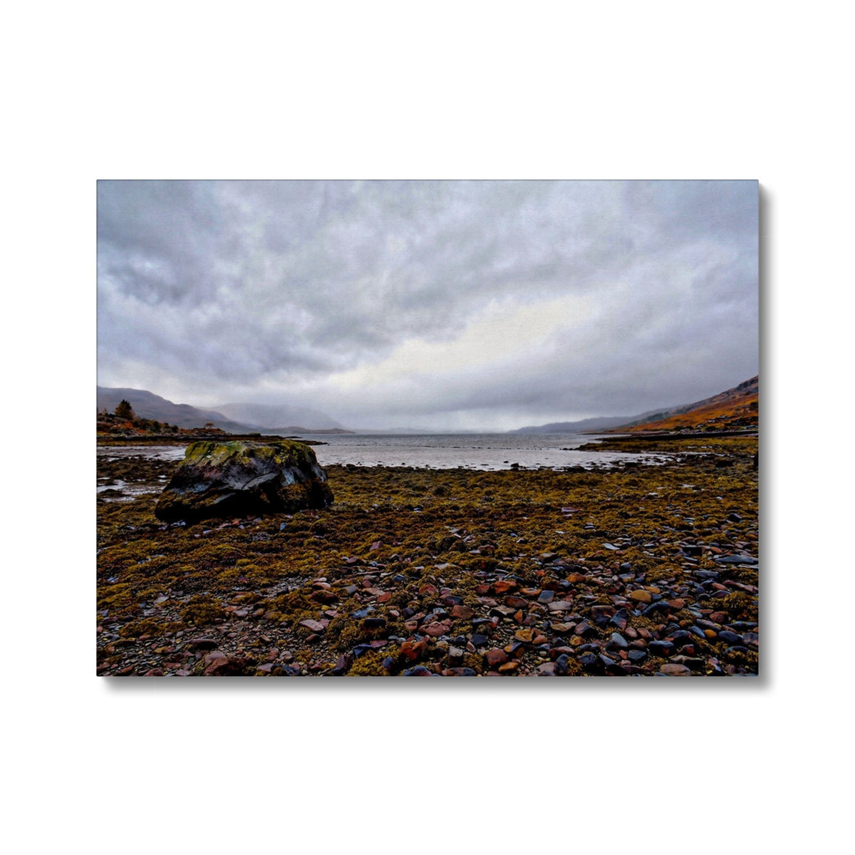Torridon pebble beach with dark rocks, green moss under cloudy sky canvas print