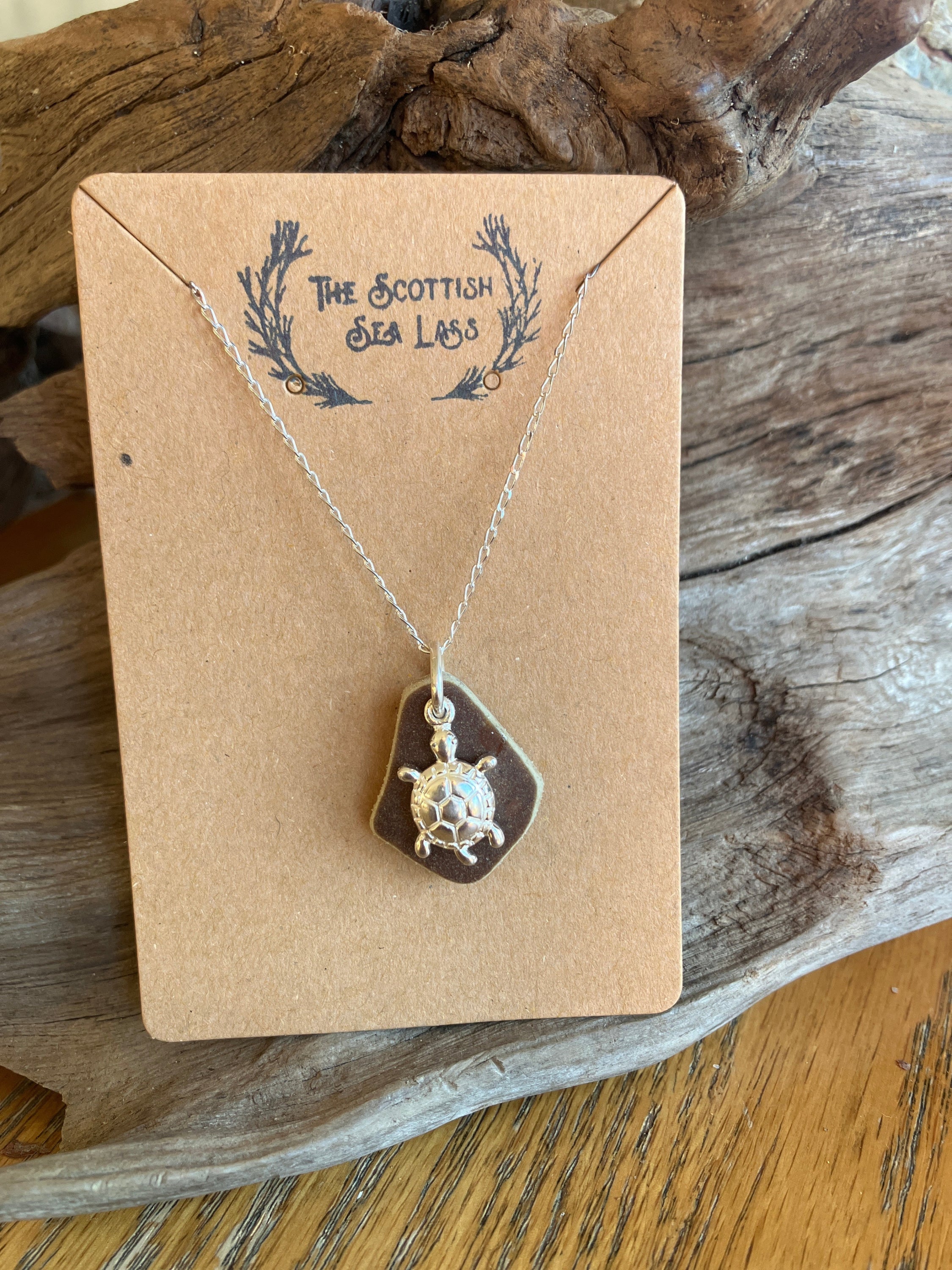 Silver turtle charm necklace with brown Sea Glass pendant on kraft paper display card