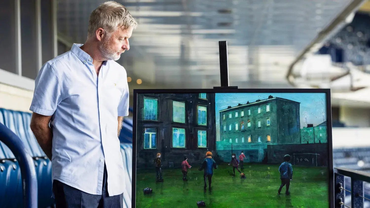 Man admiring a painting of children playing soccer at the Scottish FA exhibit