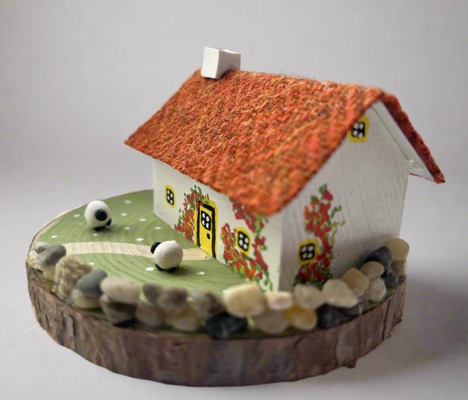 Miniature Scottish Bothy with orange thatched roof, climbing roses, sheep figurines