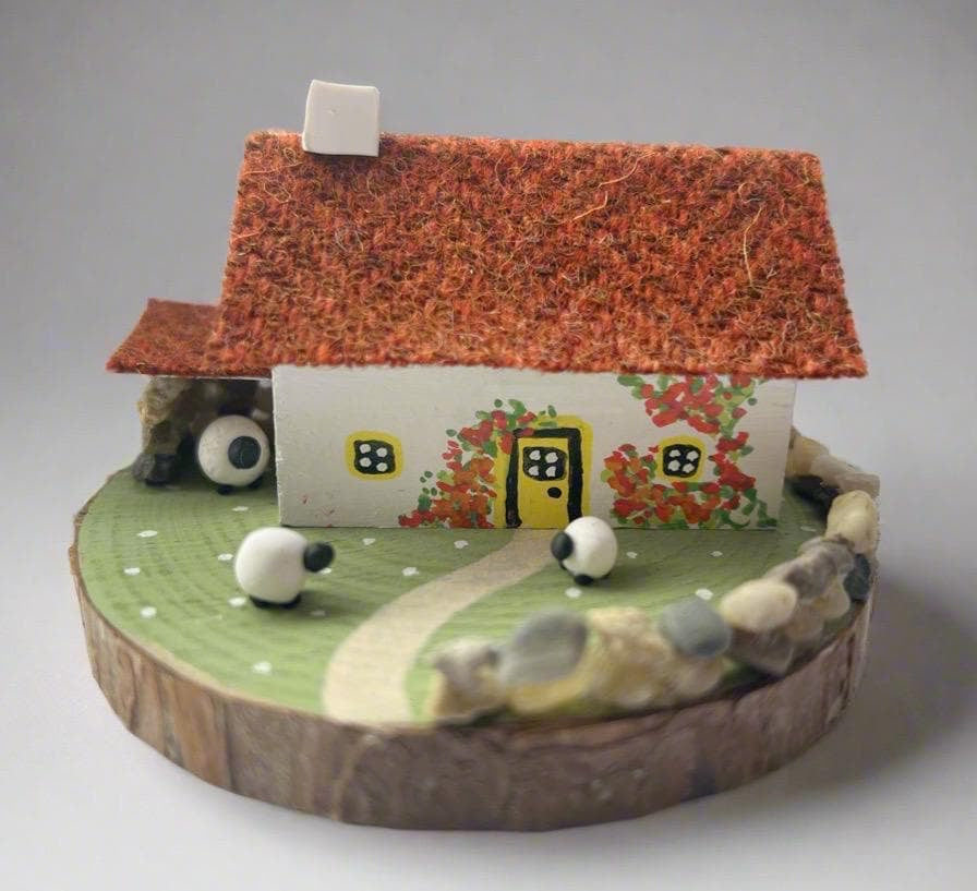 Miniature Scottish Bothy figurine with textured orange roof, white walls, red flowers, yellow door, and white sheep on green base