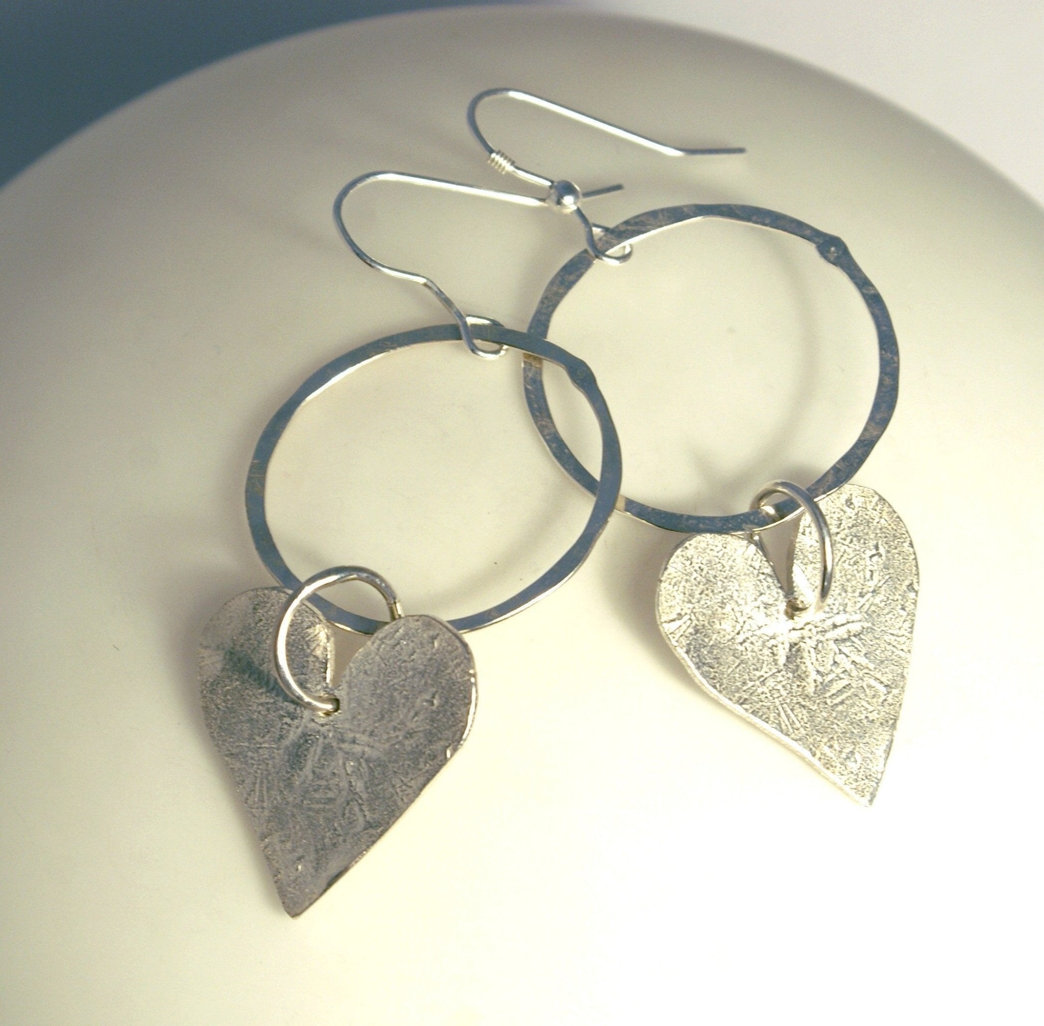 Silver heart-shaped dangle earrings with hammered texture and hoops