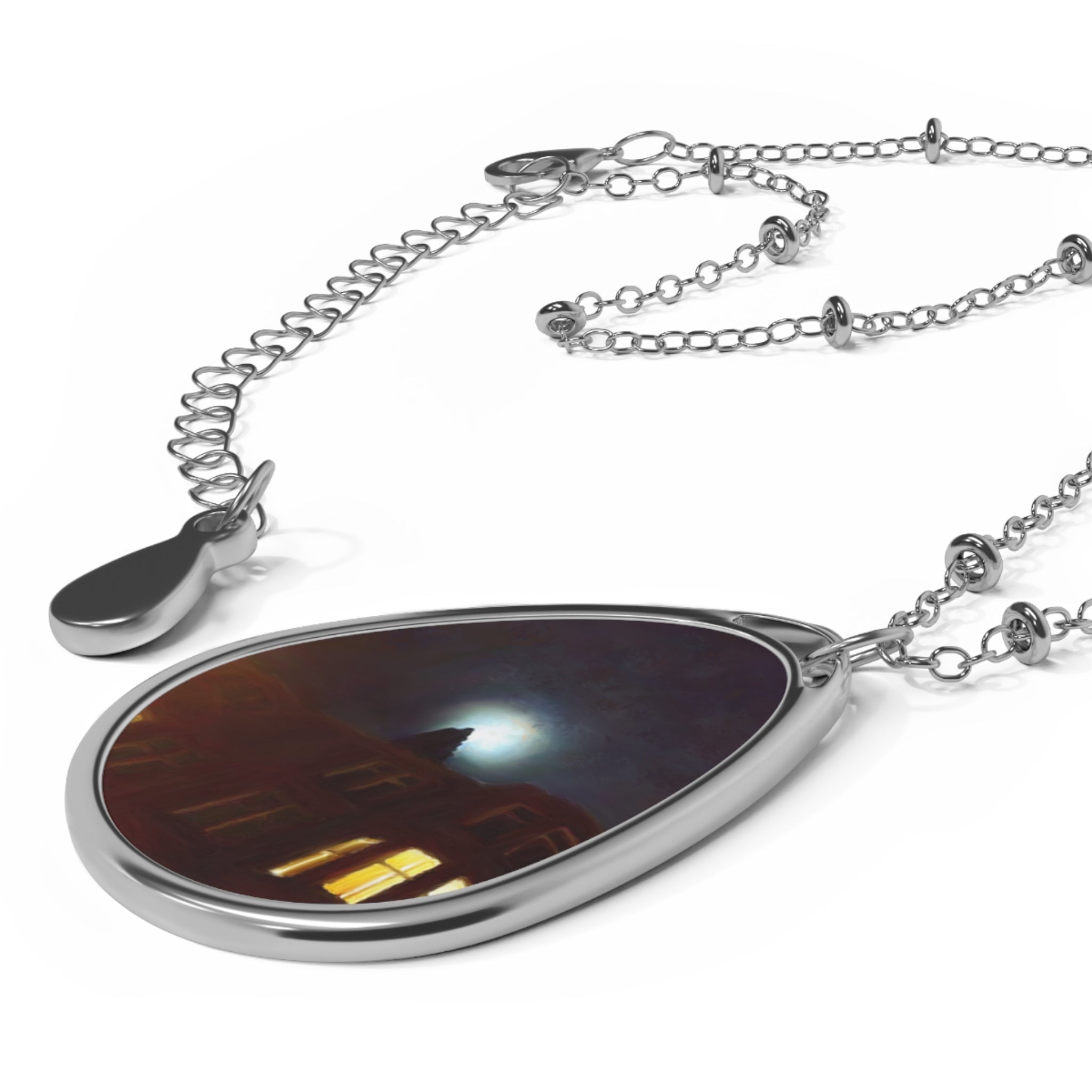 Silver-toned metal necklace with oval pendant featuring a dark abstract scene and bright light