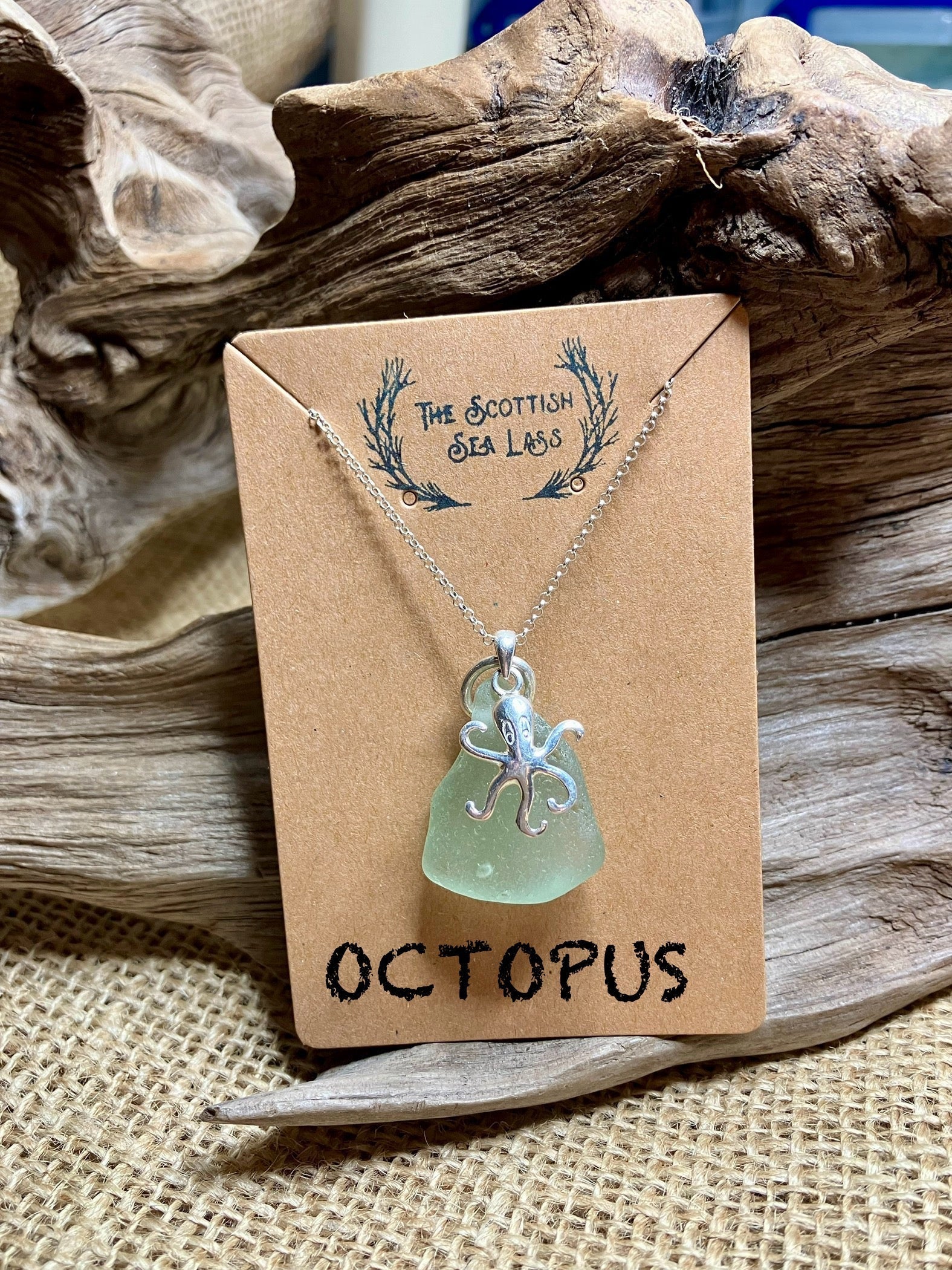 Light green sea glass pendant with silver octopus charm on silver chain displayed on brown card