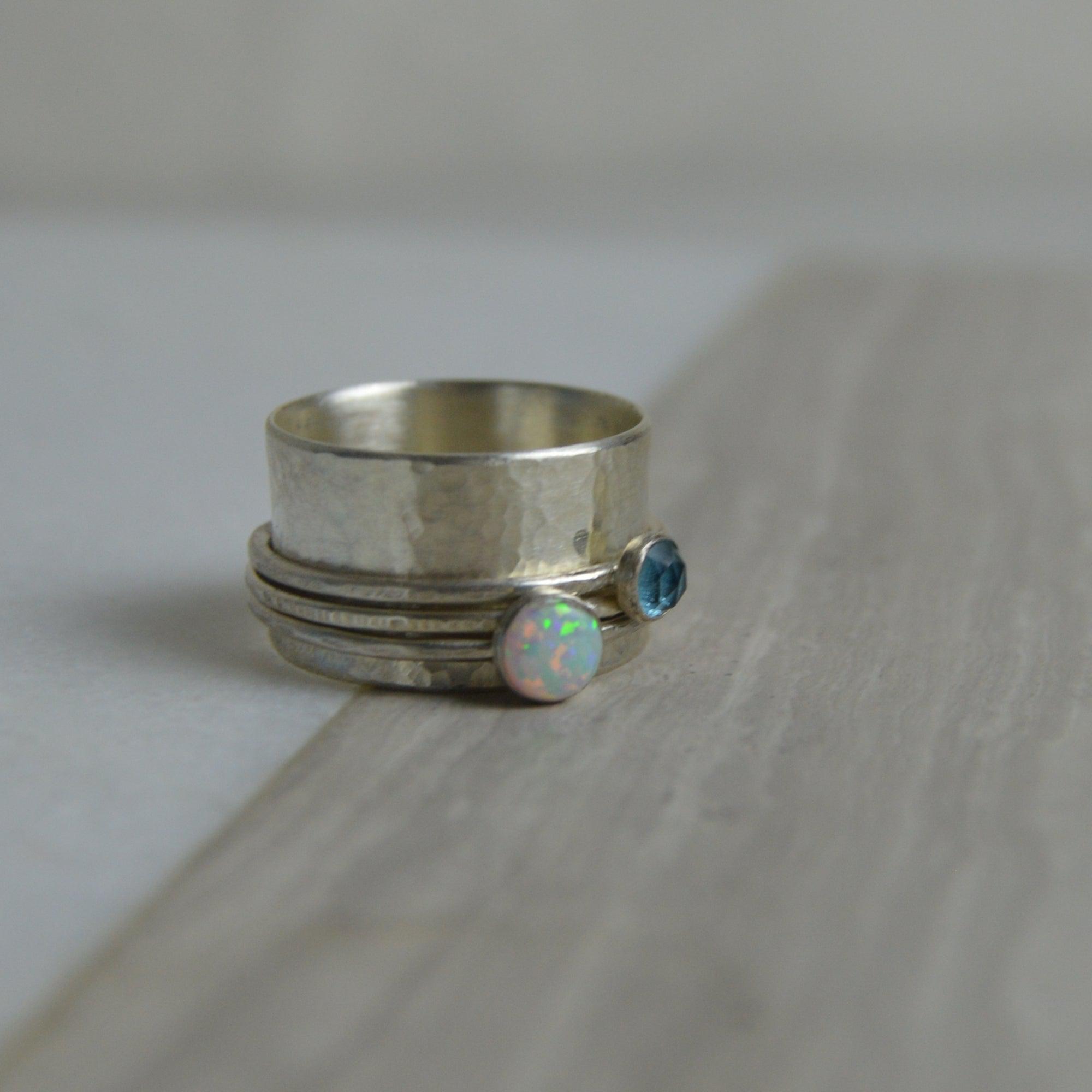 Opal and topaz spinning silver ring with hammered texture featuring iridescent opal and round blue topaz stones