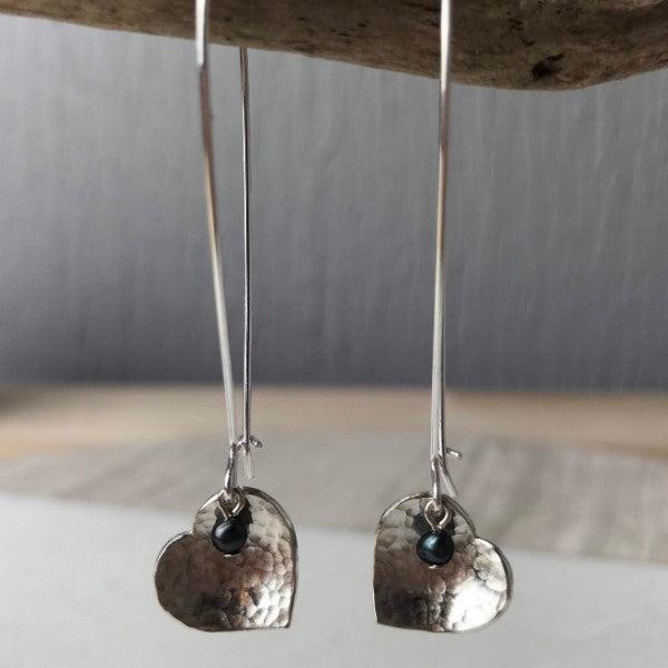 Silver heart-shaped dangle peacock pearl earrings with hammered texture and small dark gemstone accents