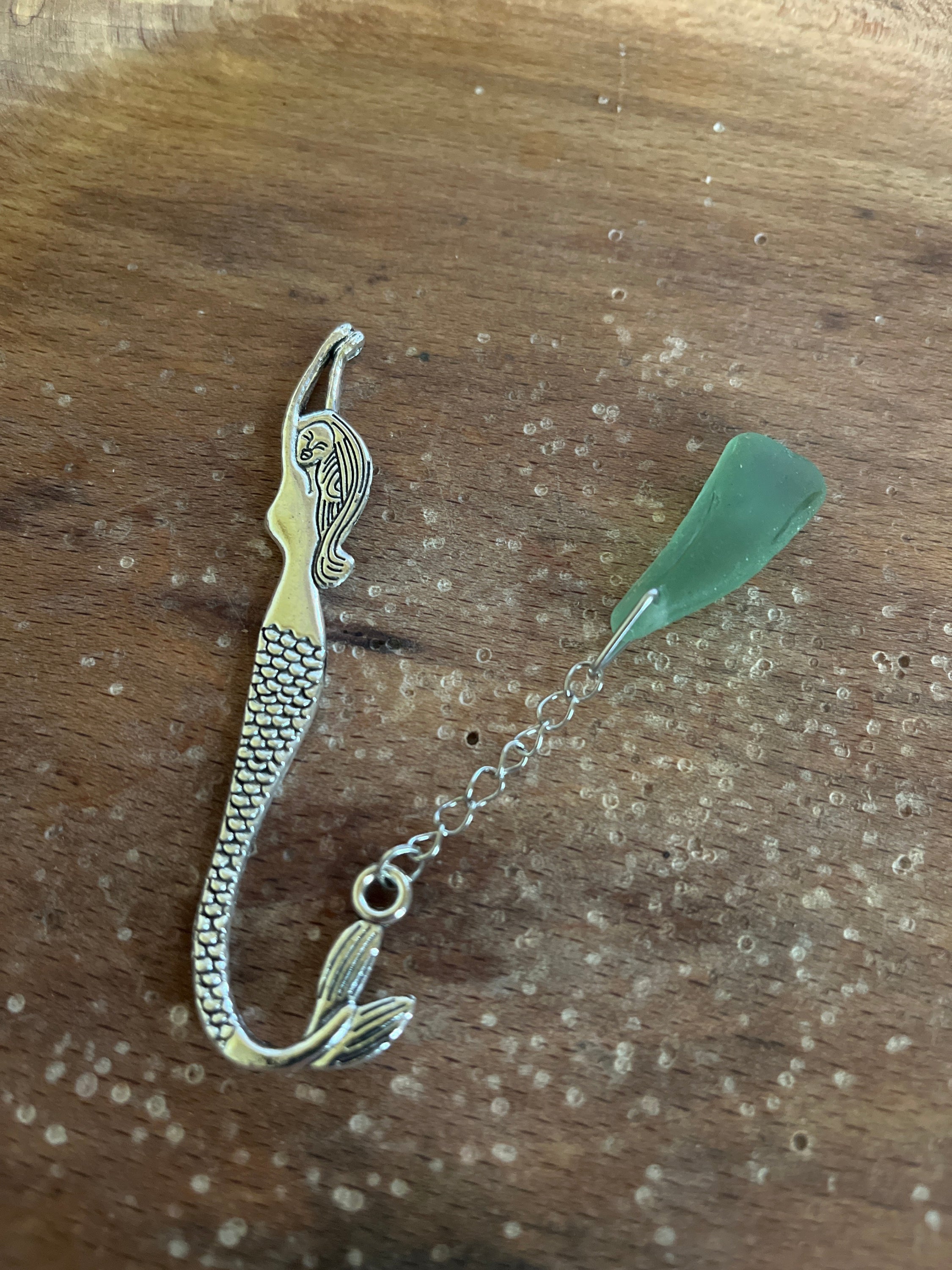Silver dragon bookmark with jade bead on open book, mermaid tails design