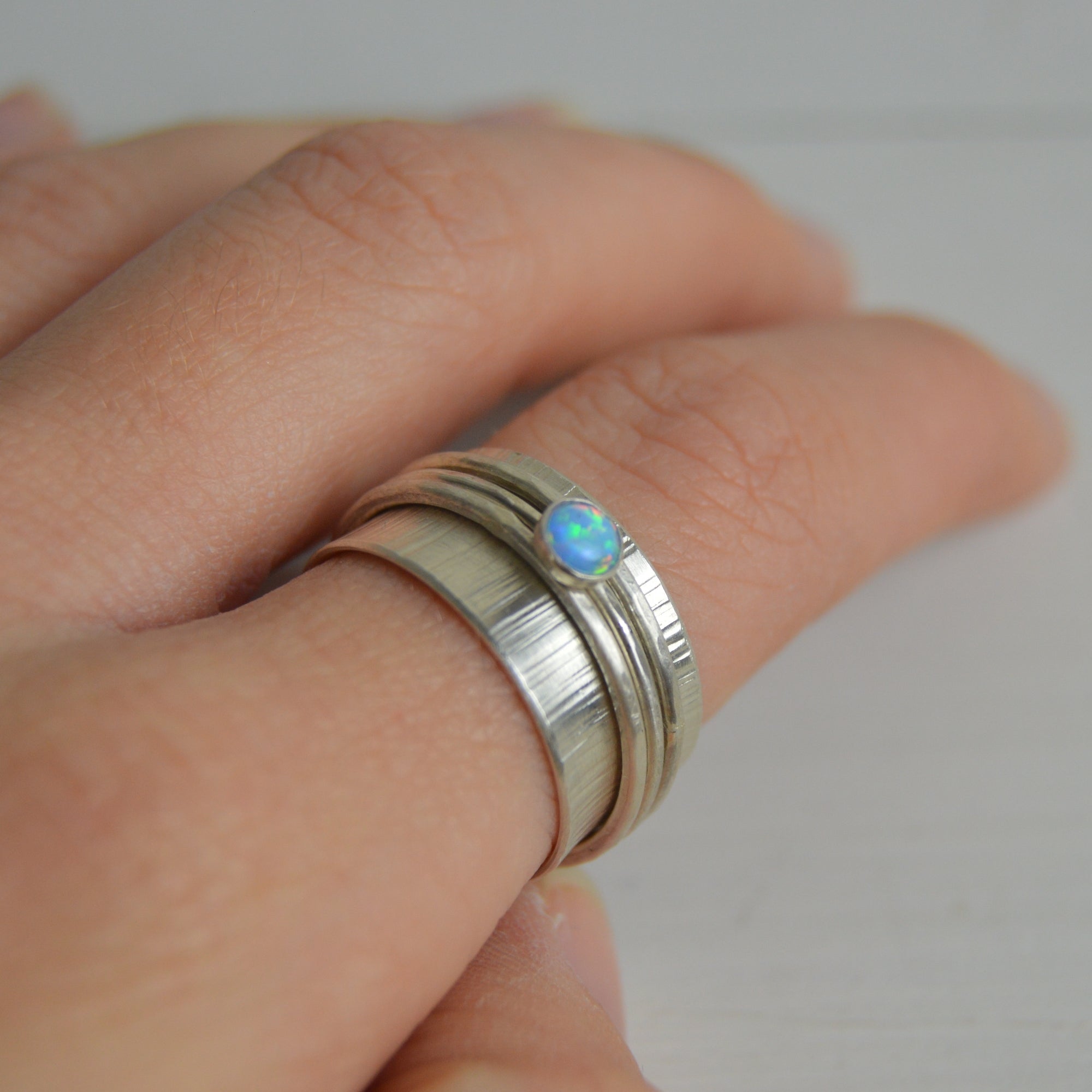 Silver opal spinning ring set with textured ridges and blue oval stone by Lindsay Mcdowall Jewellery