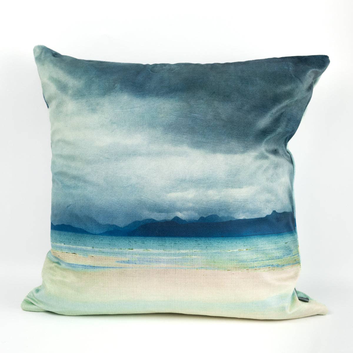 Square velvet cushion from Applecross featuring a printed landscape of misty mountains turquoise water and pale sand