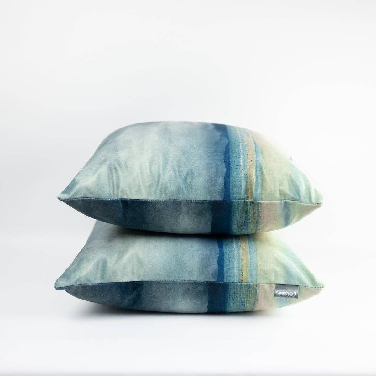 Stacked square velvet throw pillows with soft watercolor abstract design in blue teal and pale green from applecross