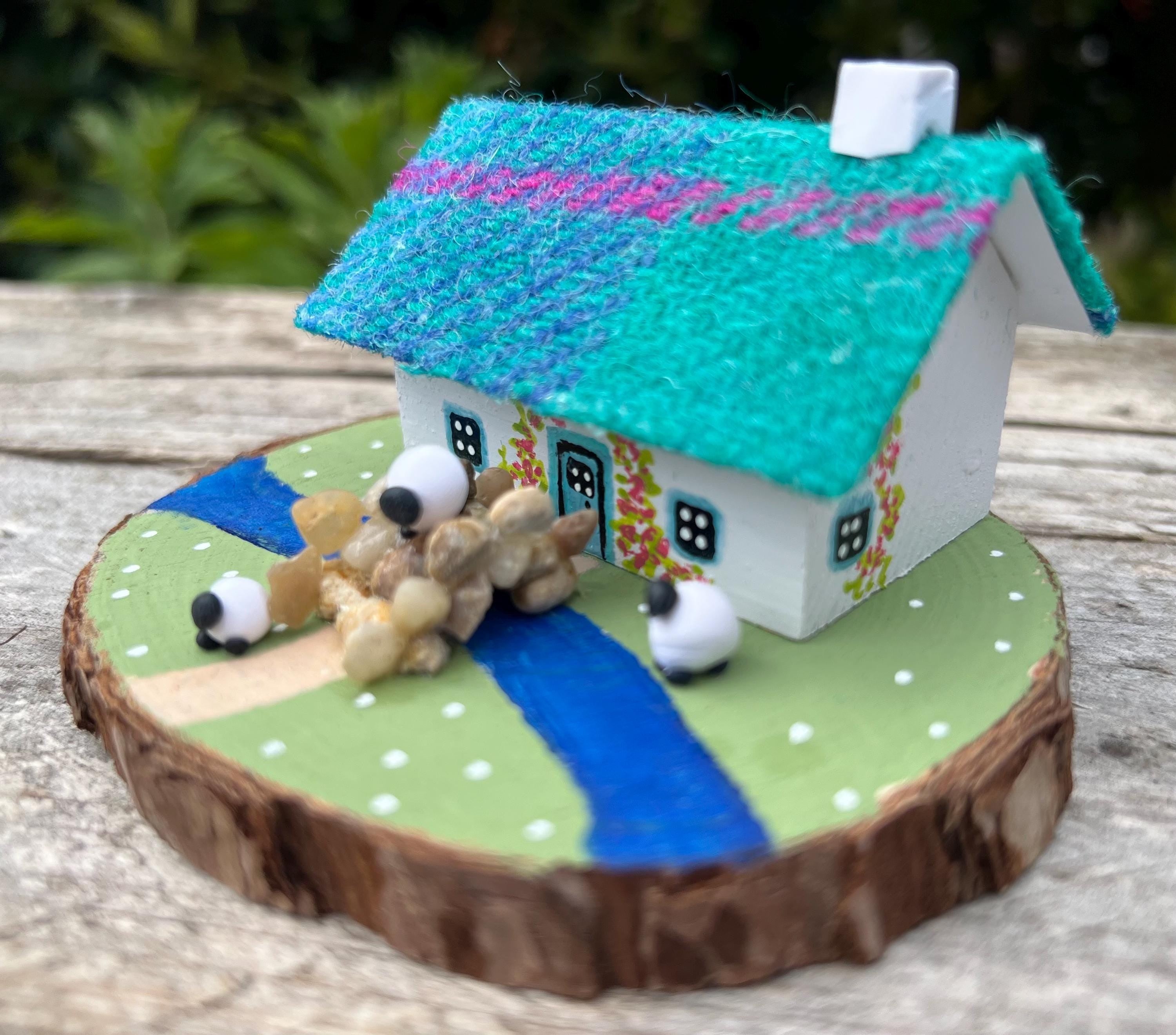 Miniature white Scottish Bothy with teal roof and three sheep figurines on painted wooden base