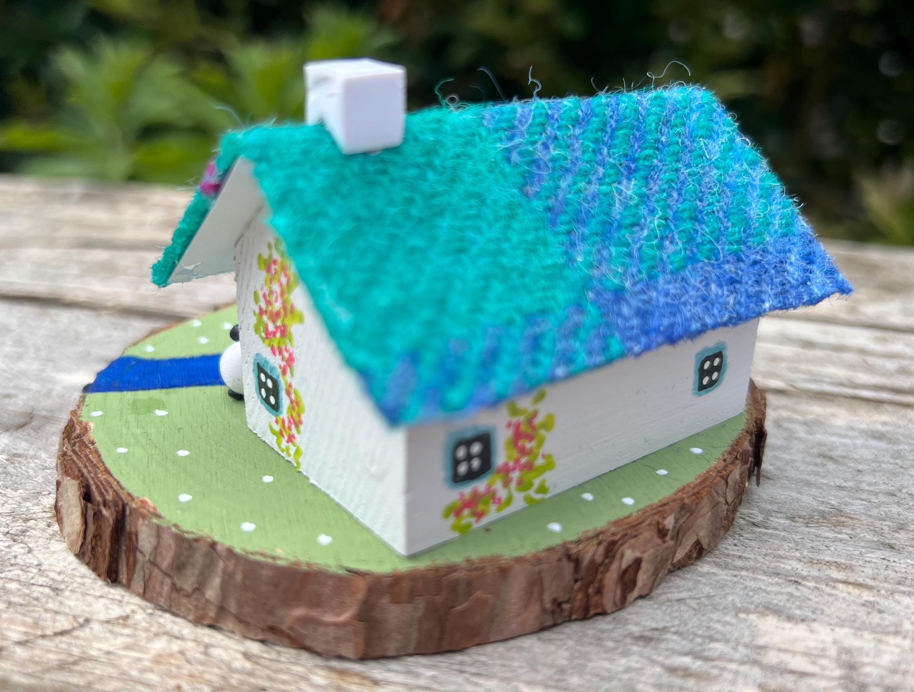 Miniature Scottish Bothy with vibrant blue and turquoise felt roof, white walls, and floral accents
