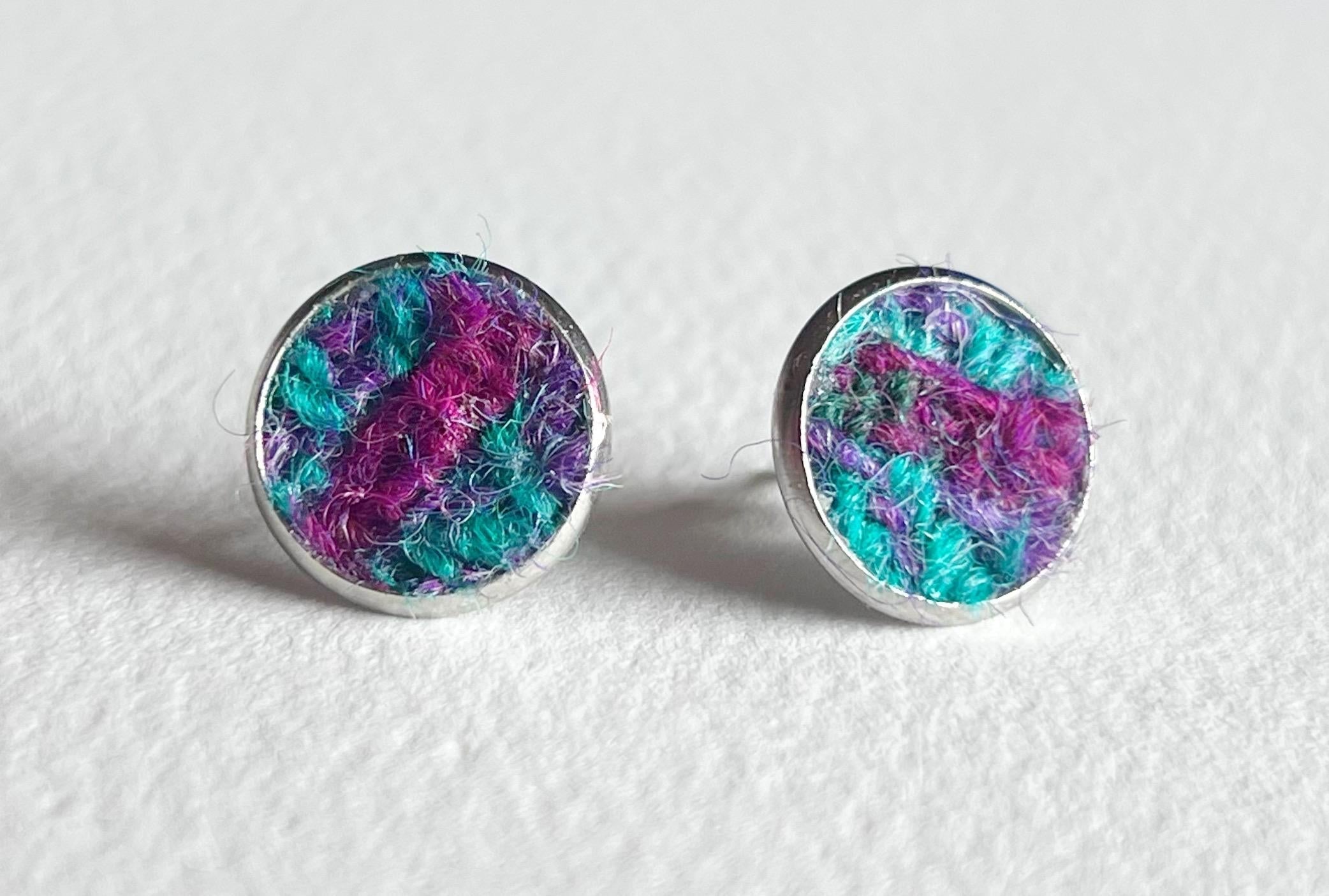 Silver-rimmed stud earrings with teal and magenta textured Harris Tweed fabric inlay