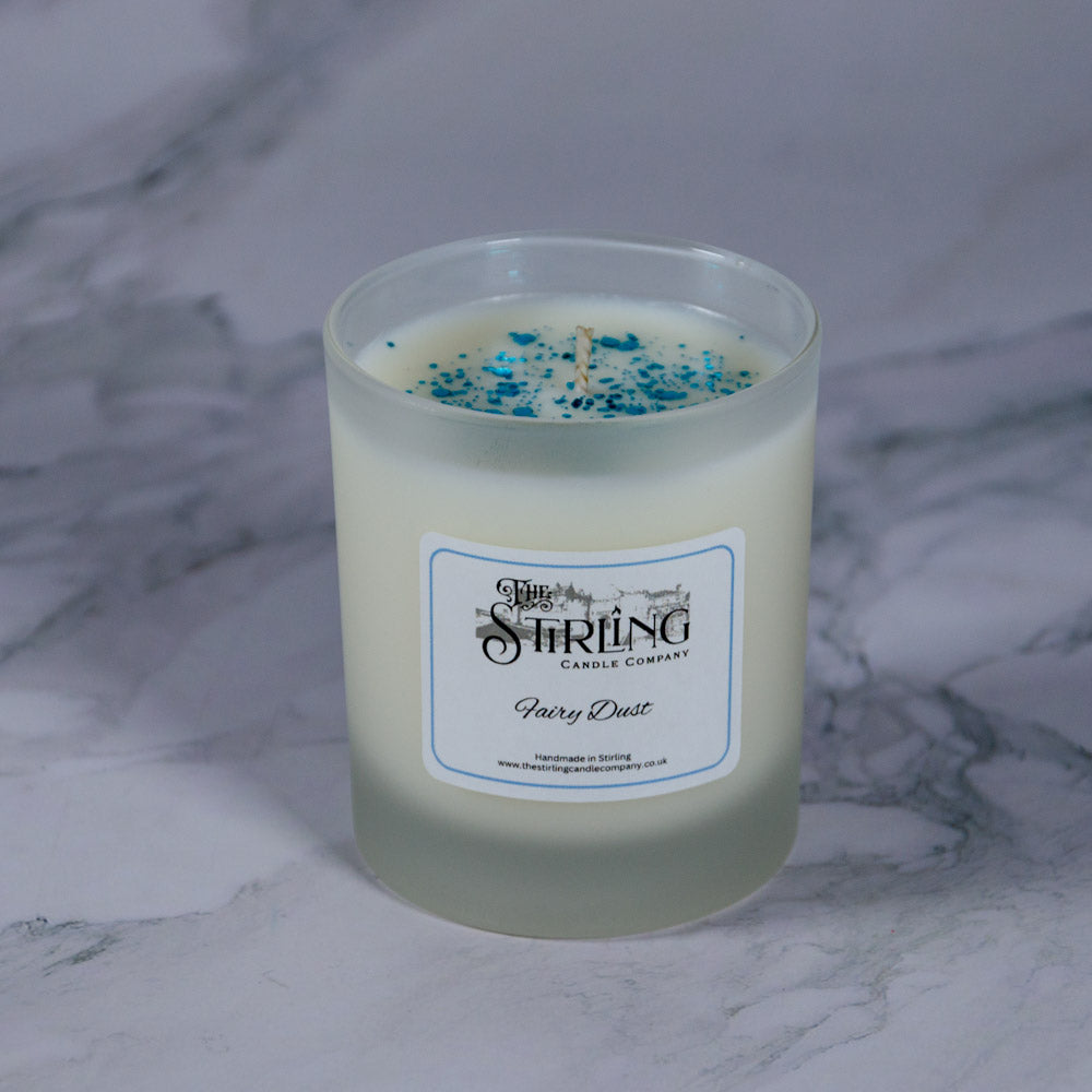 A creamy white scented fairy dust medium candle in a frosted glass jar by Stirling Candle company
