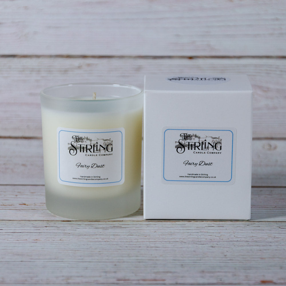A frosted glass medium candle jar with creamy white wax labeled fairy dust from the string candle company