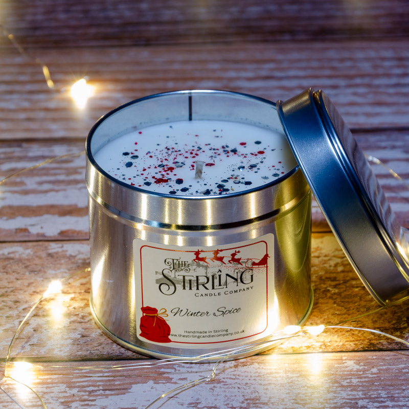 A silver tin winter spice travel candle with white wax speckled red black glitter by stirling candle company