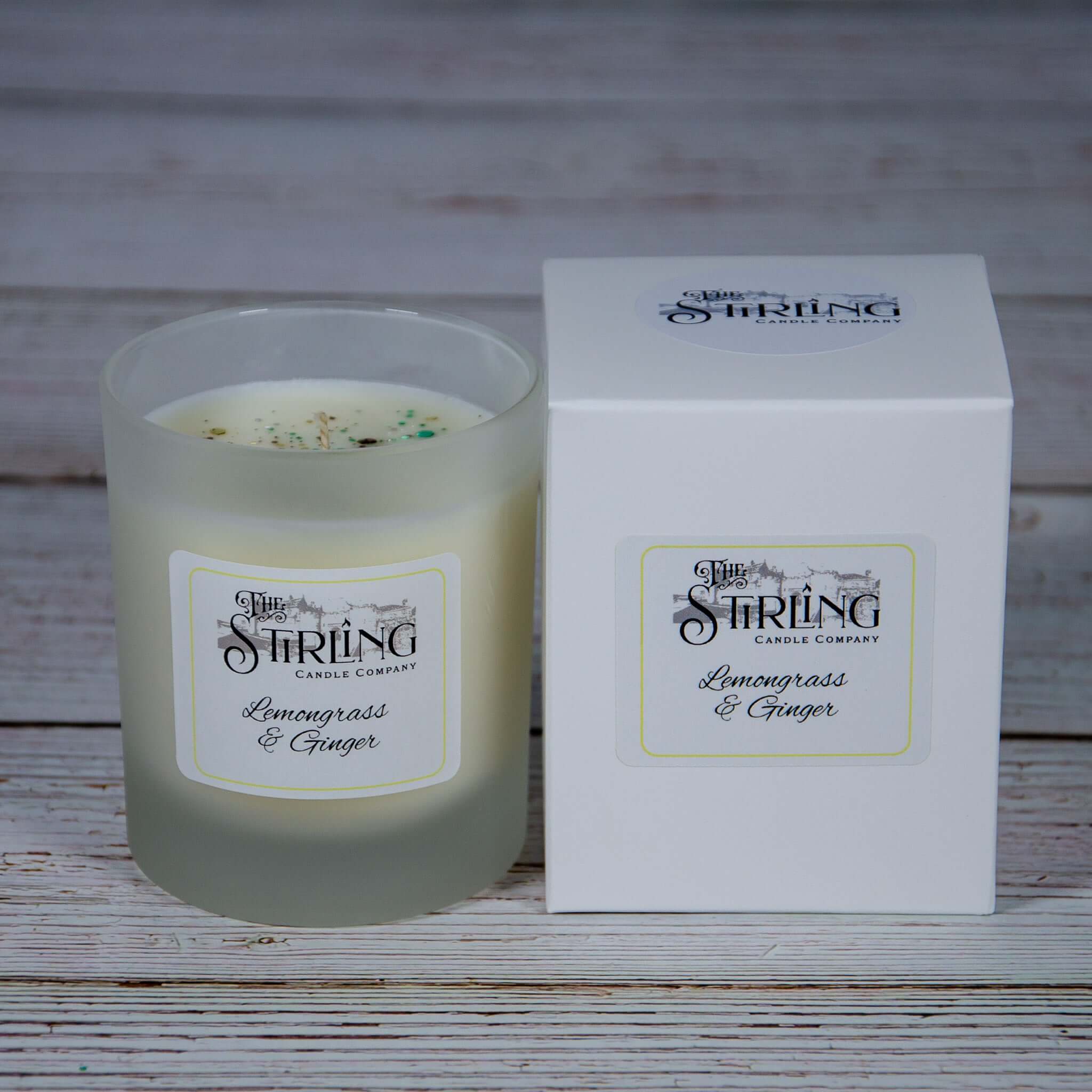 A frosted glass medium candle with white wax and green flecks labeled lemongrass and ginger by stirling candle company