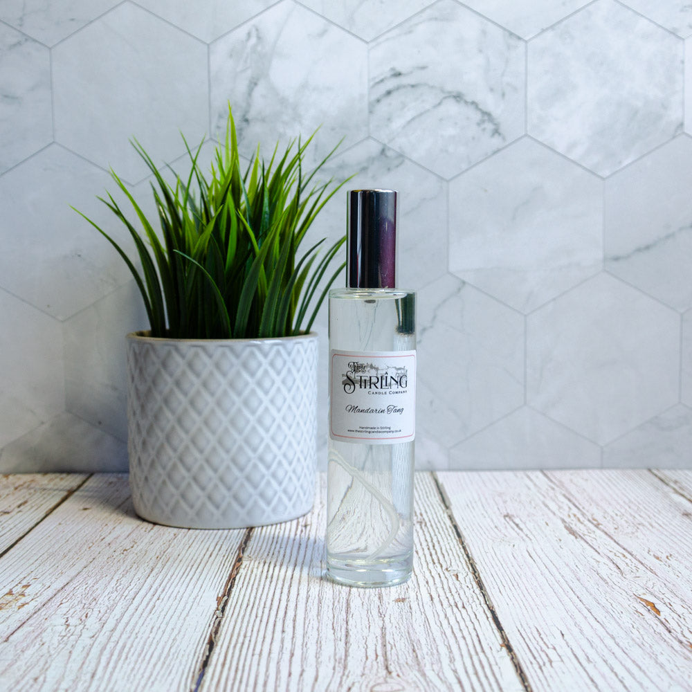 Clear spray bottle beside a textured white plant pot with green grass, set against a hexagonal tile background.