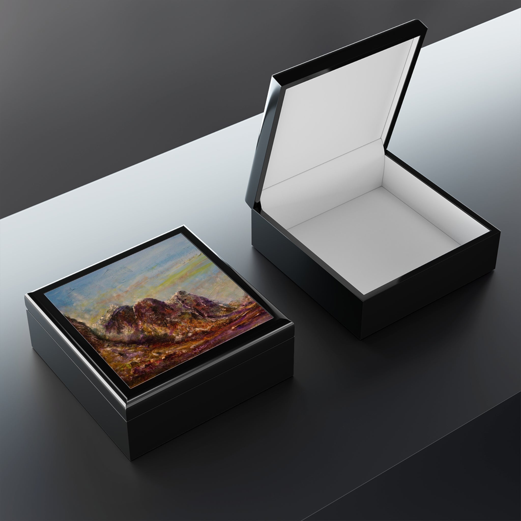 Open black leather Three Sisters Of Glencoe jewelry box revealing white interior and colorful Scottish landscape painting