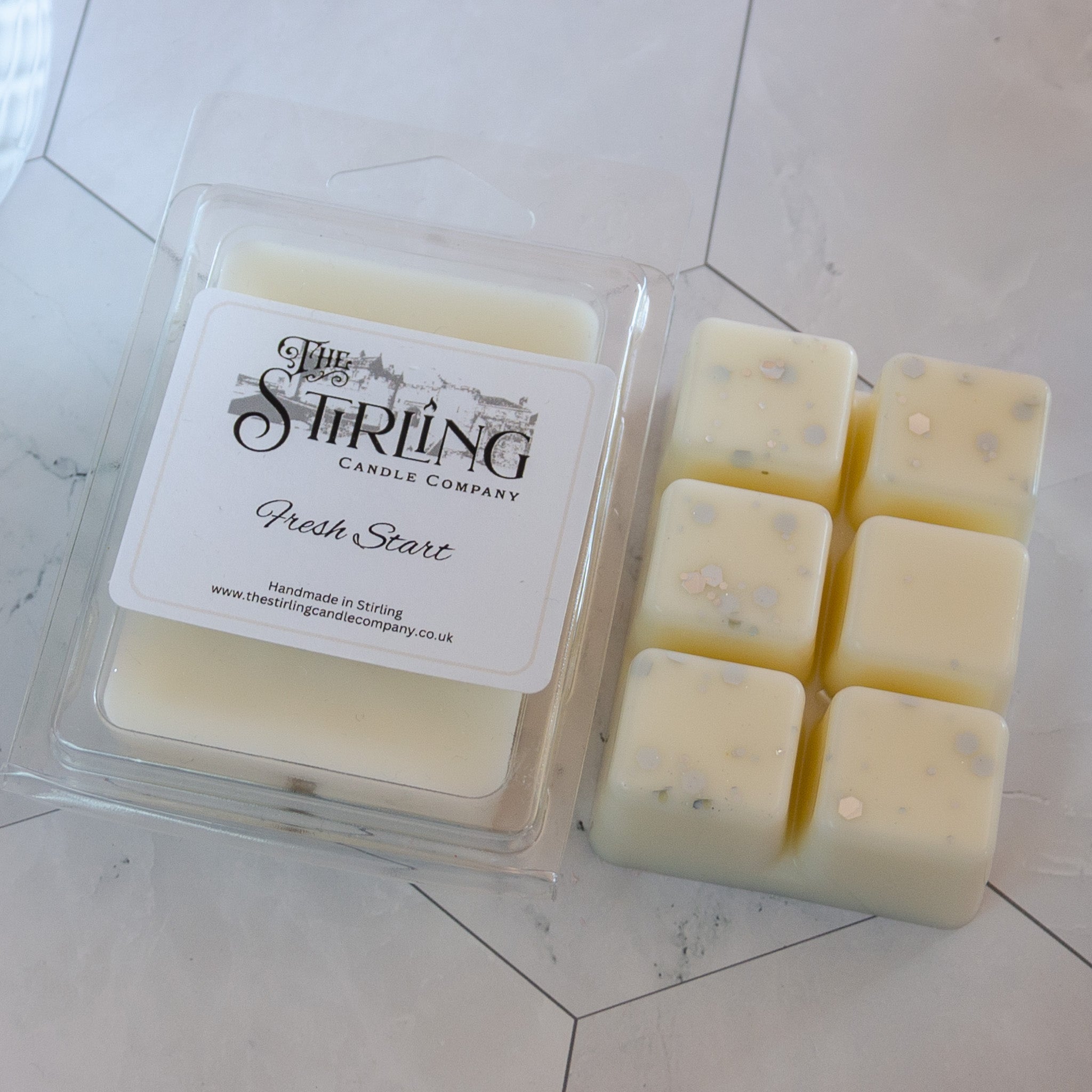 Cream-colored square wax melts with subtle speckles in clear clamshell tray by the stirling candle company fresh start scent